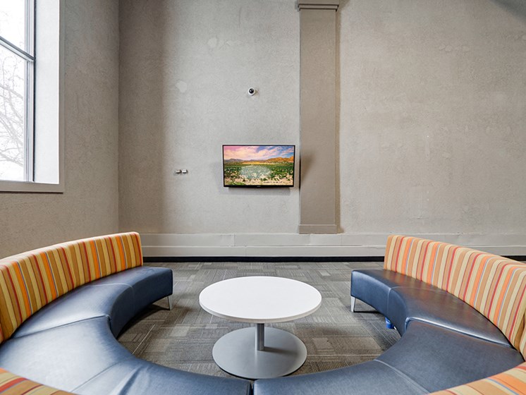 circular couch facing TV on a wall